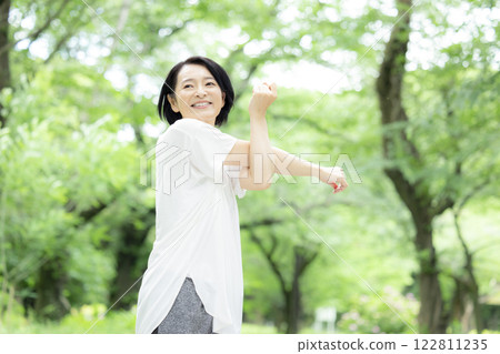 Middle-aged woman stretching in the park 122811235