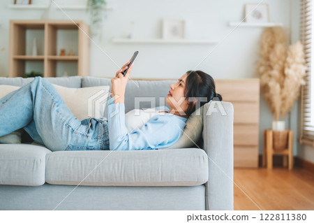 Happy cheerful positive young Asian woman on the phone at home 122811380