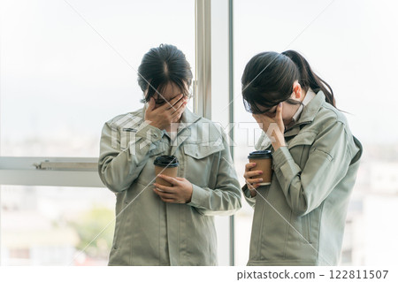 A female manufacturing worker in work clothes crying, having trouble, worrying, thinking 122811507