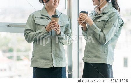 Female engineers and workers taking a break and talking at a factory or small business Female engineers and workers taking a break and talking at a factory or small business 122811508