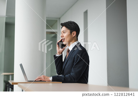 A businessman sitting in a free space and talking on a smartphone 122812641