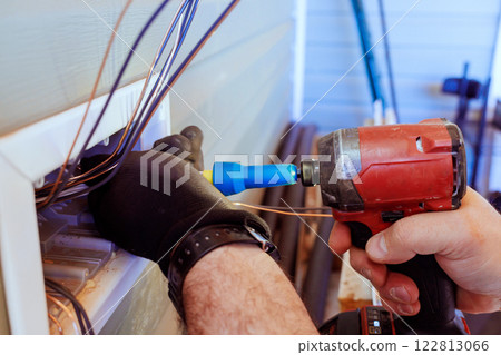 Technician worker is connecting electrical wires with screwdriver power tool while working outside house. Technician worker is connecting electrical wires with screwdriver power tool while working outside house. 122813066
