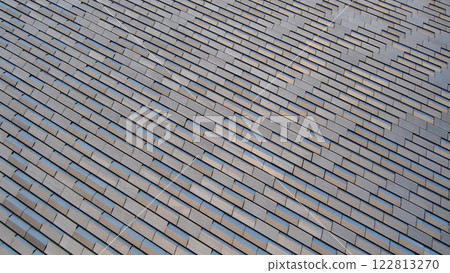 Modern Architectural Texture - A dynamic pattern of staggered metallic tiles reflecting natural light. Perfect for design inspiration, urban architecture branding, or construction material concepts 122813270