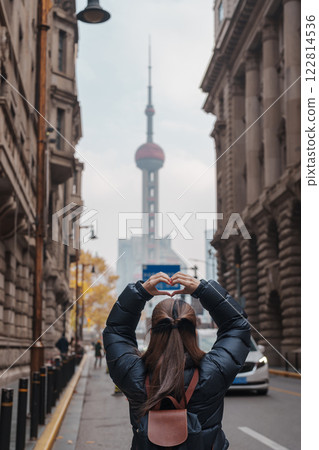 woman traveler visiting in Shanghai, China. Happy Female Tourist sightseeing Oriental Pearl Tower view in The Rock Bund of Shanghai. landmark and popular for tourism attractions. Travel and Vacation 122814536