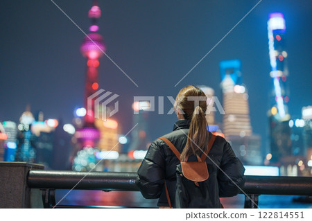 woman traveler visiting in Shanghai, China. Female Tourist with backpack sightseeing Shanghai view of Lujiazui in The Bund of Shanghai at night. landmark and popular for tourism attractions 122814551
