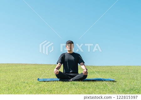 身著運動服的中年亞洲男子在草地上冥想 身著運動服的中年亞洲男子在草地上冥想 122815397
