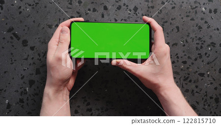 Top view man hand show smartphone with green screen on concrete background 122815710