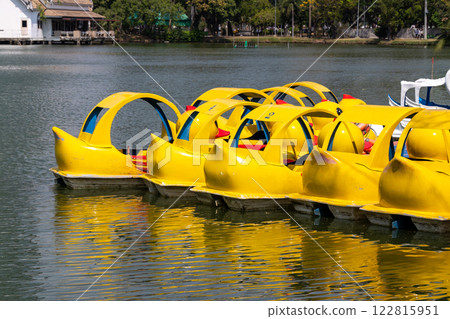 Charming yellow paddle boats ready for fun at scenic lake nature water activity tranquil viewpoint 122815951