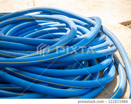 Watering the garden blue hose coiled ground outdoor setting close-up view gardening concept 122815966