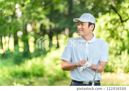 男性高爾夫球手穿著高爾夫球服在新鮮的綠色植物中 122816588