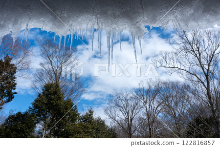 Icicles on the eaves of a mountain hut and winter forest 122816857