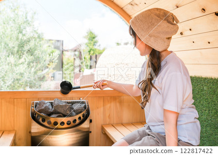 Young Asian woman wearing a sauna hat in a sauna Young Asian woman wearing a sauna hat in a sauna 122817422