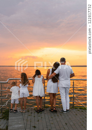 Happy family of five is standing on pier overlooking the ocean and enjoying the view and taking in the peaceful atmosphere Happy family of five is standing on pier overlooking the ocean and enjoying the view and taking in the peaceful atmosphere 122817732