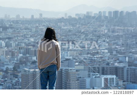 一位年輕女子，對生活感到疲憊和沮喪，從一棟高層建築上俯瞰這座城市 122818897