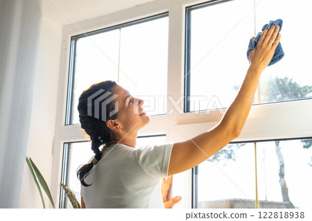 Woman manually washes the window of house with rag cleaner and mop inside the interior with home plants on windowsill. Restoring order and cleanliness in the spring, cleaning servise Woman manually washes the window of house with rag cleaner and mop inside the interior with home plants on windowsill. Restoring order and cleanliness in the spring, cleaning servise 122818938