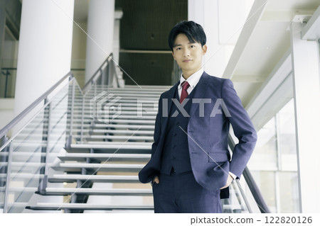 一位年輕商人站在辦公大樓樓梯上的肖像 122820126
