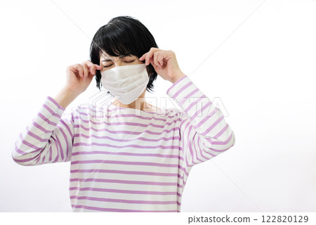 A middle-aged woman who seems uncomfortable wearing a mask 122820129