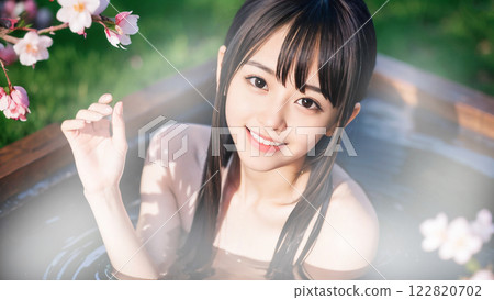 A young woman bathing in an open-air hot spring bath with cherry blossoms A young woman bathing in an open-air hot spring bath with cherry blossoms 122820702