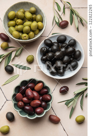 Assorted olives in ceramic bowls with leaves 122822265