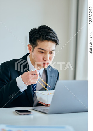 一名 20 多歲的年輕男子邊工作邊吃泡麵 一名 20 多歲的年輕男子邊工作邊吃泡麵 122822694