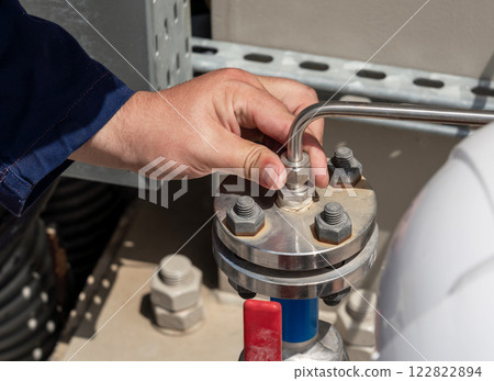 Close-up of an engineer adjusting a pipeline flange connection, ensuring precision and operational reliability Close-up of an engineer adjusting a pipeline flange connection, ensuring precision and operational reliability 122822894