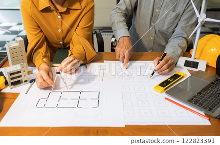 Drawing working on blueprint meeting for project working with partner on model building at company office. Drawing working on blueprint meeting for project working with partner on model building at company office. 122823391