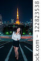 A woman posing with a smile against the backdrop of a tower at night 122823538