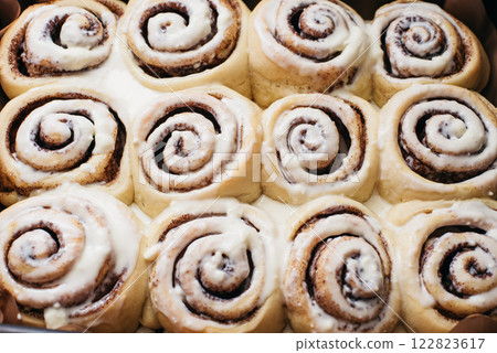 Freshly sweet baked cinnabon buns with cream chees sauce on baking paper. homemade rolls with Cinnabon cinnamon. Selective focus. French buns swirl, snail with glaze with cinnamon and cream Freshly sweet baked cinnabon buns with cream chees sauce on baking paper. homemade rolls with Cinnabon cinnamon. Selective focus. French buns swirl, snail with glaze with cinnamon and cream 122823617