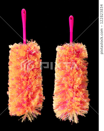 Orange microfiber Duster stick made from synthetic to clean house dust and web. Room Ceiling and window covered with dust bunnies, cobweb cleaned by microfiber duster stick. Black background isolated 122823834