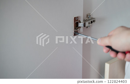 Installing furniture hinge with screwdriver 122824403