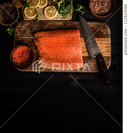 Raw salmon fillet with knife and spicies on wooden table. Healthy red omega fish and lemons at kitchen, view from above 122824568
