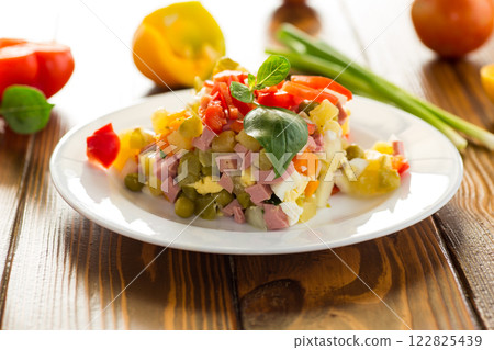 vegetable salad of boiled vegetables, with peas, sausage, sweet pepper. On a wooden table vegetable salad of boiled vegetables, with peas, sausage, sweet pepper. On a wooden table 122825439