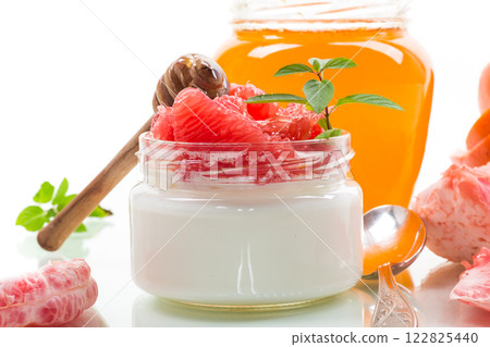 homemade sweet yogurt in a glass jar with pieces of red ripe grapefruit and honey, isolated on white background homemade sweet yogurt in a glass jar with pieces of red ripe grapefruit and honey, isolated on white background 122825440