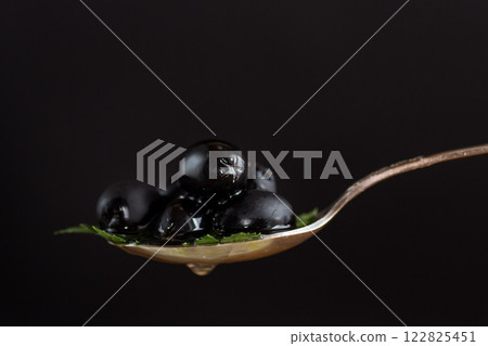 black olives in a spoon isolated on a black background 122825451