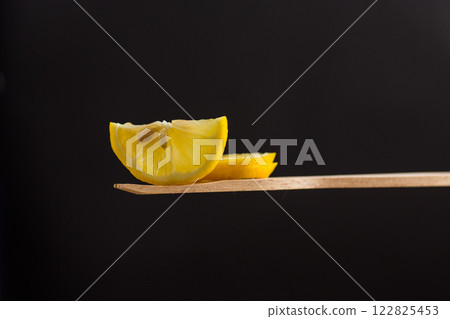 slice of fresh juicy lemon on wooden spatula isolated on black background 122825453