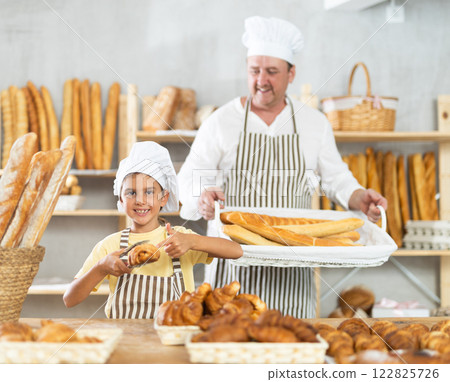 Baker dad and daughter are standing near product range in bakery kitchen. 122825726