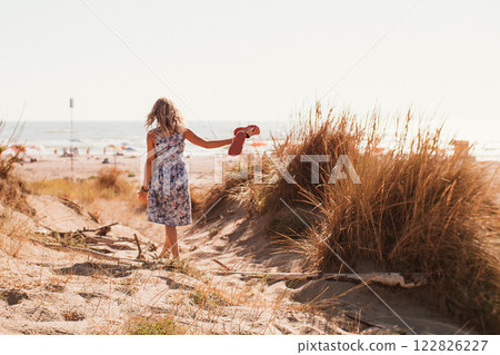 Bambina walks to sea along path among sand dunes 122826227
