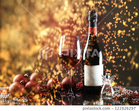 Christmas and New Year. Festive decorations, bottle of red wine and glass on the dark background. Happy New Year and Christmas. Bokeh light soft effect 122826297