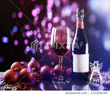 Christmas and New Year. Festive decorations, bottle of red wine and glass on the dark background. Happy New Year and Christmas. Bokeh light soft effect 122826298