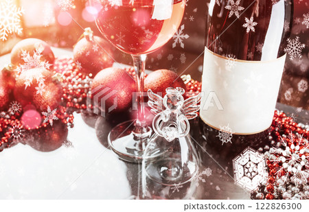 Christmas and New Year. Festive decorations, bottle of red wine and glass on the dark background. Happy New Year and Christmas. Bokeh light soft effect 122826300
