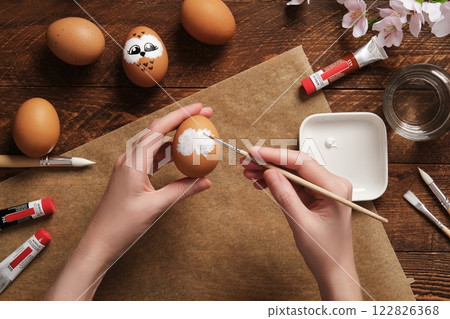 Women's hands painting on brown eggshells. Preparation for the celebration of Easter. Painting Easter eggs with acrylic pigment dyes in tubes. Women's hands painting on brown eggshells. Preparation for the celebration of Easter. Painting Easter eggs with acrylic pigment dyes in tubes. 122826368