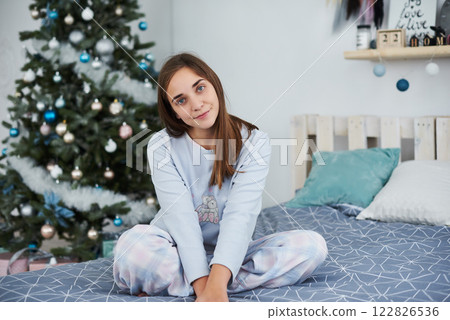 Beautiful girl lies on a bed in pajamas on Christmas morning Beautiful girl lies on a bed in pajamas on Christmas morning 122826536