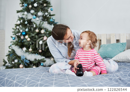 happy family mother and child daughter on Christmas morning at the Christmas tree with gifts happy family mother and child daughter on Christmas morning at the Christmas tree with gifts 122826544