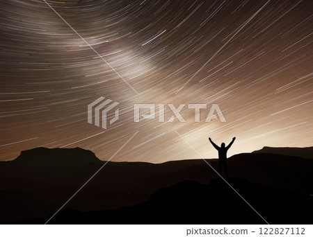 Silhouette of a happy photographer adventure trekking on mountain with real fantasy moving stars in the night sky. Conceptual of amazing nature with great dream journey and voyage scene Silhouette of a happy photographer adventure trekking on mountain with real fantasy moving stars in the night sky. Conceptual of amazing nature with great dream journey and voyage scene 122827112