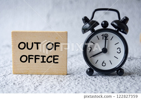 Out Of Office text on wooden square with table clock background Out Of Office text on wooden square with table clock background 122827359