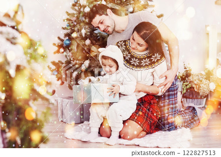 Happy family at christmas in morning opening gifts together near the fir tree. The concept of family happiness and well-being Happy family at christmas in morning opening gifts together near the fir tree. The concept of family happiness and well-being 122827513