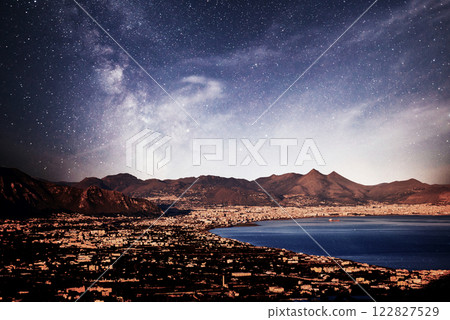 old town by the sea, low mountains in the background, dramatic star sky. 122827529