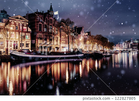 Beautiful night in Amsterdam. Night illumination of buildings and boats near the water in the canal during a snowstorm. Bokeh light effect, soft filter 122827805