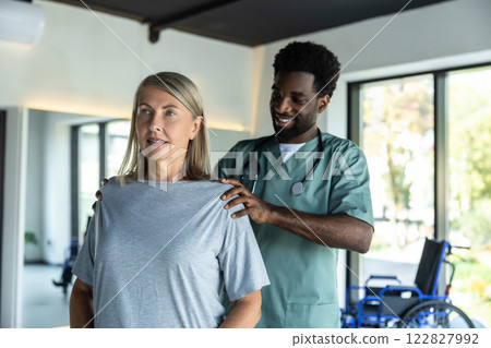 African american male doctor working on correction of female patients posture 122827992