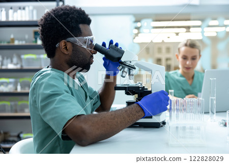 Man medical worker working in advanced scientific lab with microscope doing medicine research 122828029